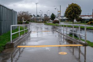 Wet concrete public footpath and access ramp during rainfall showing increased slip risk in municipal setting