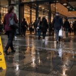 Shopping centre entrance with wet floor conditions and high pedestrian traffic highlighting slip risk in public environments
